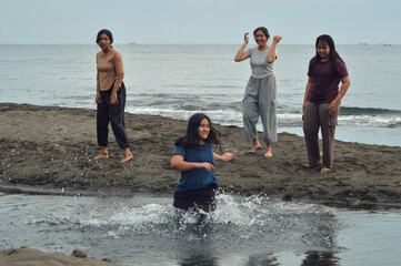 One girl excitedly runs into the brackish stream while her three friends watch and laugh on the...