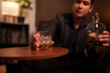 Businessman holding a glass of whiskey in a restaurant sitting on a sofa