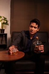 Businessman holding a glass of whiskey in a restaurant sitting on a sofa