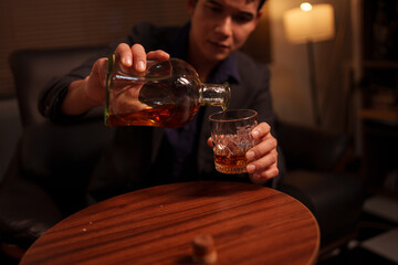 Businessman holding a glass of whiskey in a restaurant sitting on a sofa