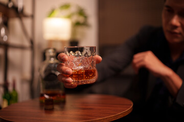 Businessman holding a glass of whiskey in a restaurant sitting on a sofa