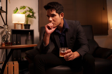 Businessman holding a glass of whiskey in a restaurant sitting on a sofa