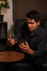 Businessman holding a glass of whiskey in a restaurant sitting on a sofa