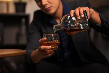 Businessman holding a glass of whiskey in a restaurant sitting on a sofa