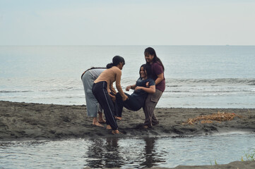 A soaked teen girl is lifted by her three laughing friends as they enjoy a lively morning on the...