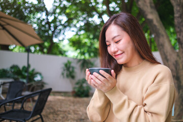 Portrait image of a woman holding and drinking coffee in the outdoors cafe