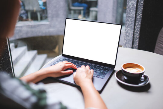 Mockup image of a woman working and typing on laptop computer with blank white desktop screen in cafe