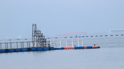 Fototapeta premium a float or pontoon, made from a used barrel or drum, used to float a net or structure in water, such as in fish farming in floating cages.