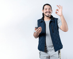 Smiling man gesturing approval with his phone in hand. Young man gesturing approval on the...