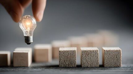 Hand Placing Lightbulb on Wooden Blocks: Idea, Innovation, and Growth