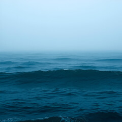 Fototapeta premium A misty, expansive ocean scene; dark teal water with small waves near the bottom, gradually lightening to a hazy blue-grey horizon