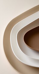 Three nested, curved, neutral-toned plates, stacked in a  soft light