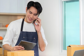 E-commerce. Employee on phone while checking tablet in shipping area.
