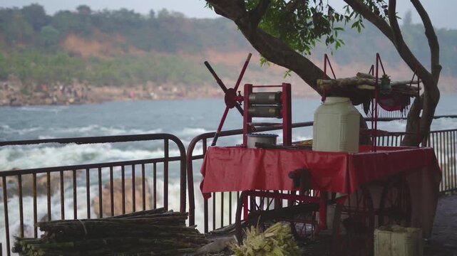 a sugarcane juice stall with Dhuandhar water falls in background at bhedaghat in madhya pradesh india