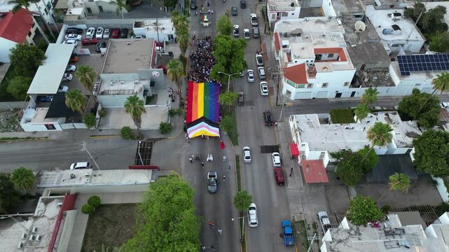 Giant pride flag waving at a march in a city with hundreds of participants