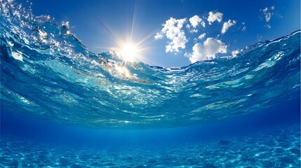 Fototapeta premium Underwater view of vibrant blue water and a bright sunlit sky.