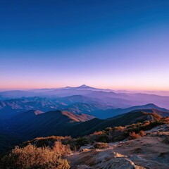 Scenic mountain landscape at dawn with layered rolling hills and distant snow-capped peak under a colorful sky, capturing the serenity and beauty of nature in sunrise light