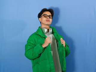 Confident young Asian man in a green winter jacket, pointing to himself with an arrogant...