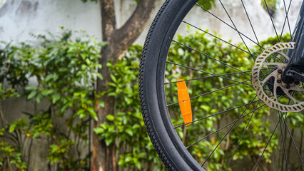Close up shot of a bicycle wheel with a disc brake and orange reflector, set against a natural...