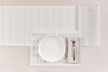 Boho minimal brunch table setting with layered fringed placemats in natural tones, white ceramic...