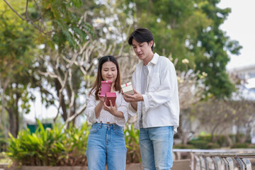 Fototapeta premium Asian Couple Exchanging Gifts Outdoors