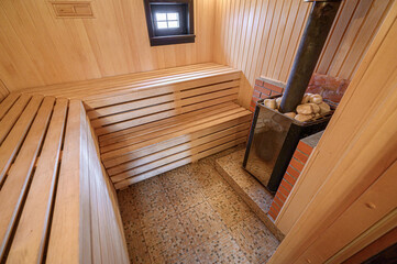 Cozy sauna interior. Wooden benches line the walls, with a stove and stones in the corner