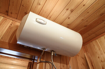 low-angle shot shows a white water heater mounted on a wall with wooden paneling