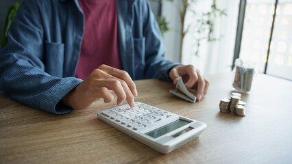 Man calculates finances by calculator Count banknotes and coinsใ