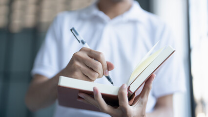 man is holding notebook and pen writing moment of creativity or documentation