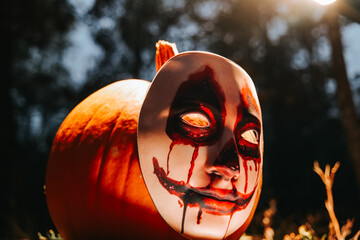 Halloween holiday. Halloween wallpaper with a scary pumpkin in a forest.Ominous fear atmosphere 
