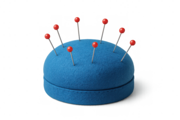 Fabric pincushion in blue, studded with red pins, highlighting sewing and crafting workspace essentials