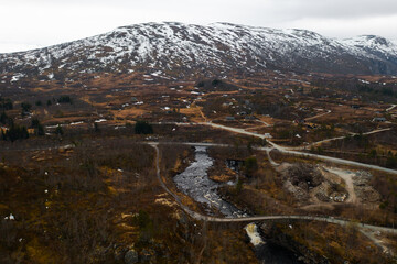 Majestic canyon leads to Voringsfossen revealing towering rugged cliffs and winding river. Distant mountains frame dramatic vast Norwegian landscape
