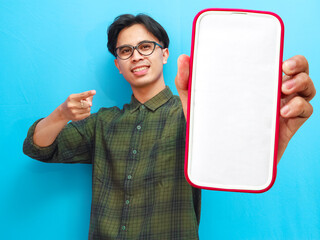 Smiling happy young Asian man showing a blank phone screen on isolated white background for...