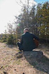 Beautiful blonde man playing acoustic guitar and singing relaxing enjoying outdoors on sunny autumn...