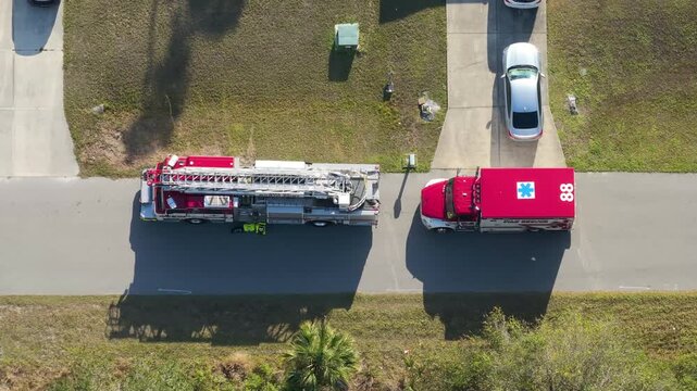 Paramedics assist patient at suburban home as ambulance and fire engine remain stationed outside.