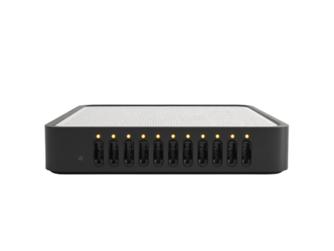 A rectangular, dark gray device with a light gray textured top surface.  Several small, illuminated yellow lights are visible.  Numerous ports are aligned along the bottom edge