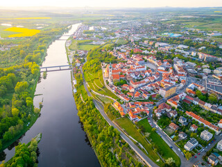 This aerial view captures Melnik City and its stunning chateau perched above the Labe River. The vibrant landscape showcases nearby greenery and the river's gentle flow.