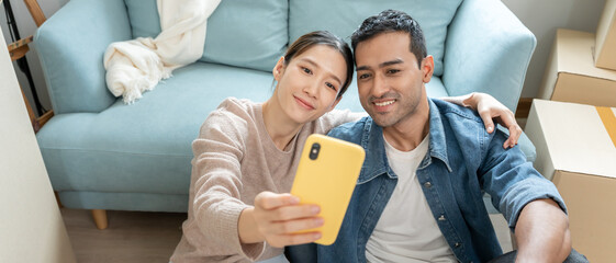 Moving house, relocation. Couple selfie during move furniture for new home, inside the room was a...