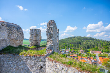 Rabi Castle's ruins stand prominent against a clear blue sky, surrounded by lush greenery and quaint village views, showcasing Czechia's rich historical landscape.