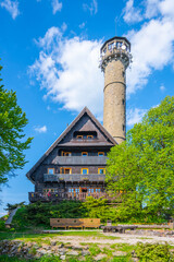 Svatobor lookout tower stands tall against a bright blue sky, surrounded by vibrant trees and greenery. Visitors can enjoy beautiful views from this charming structure set in nature.
