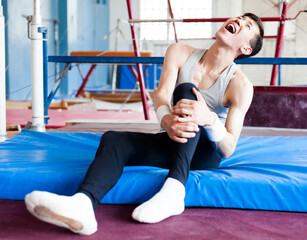 Injured male gymnast suffering from knee pain after bad landing