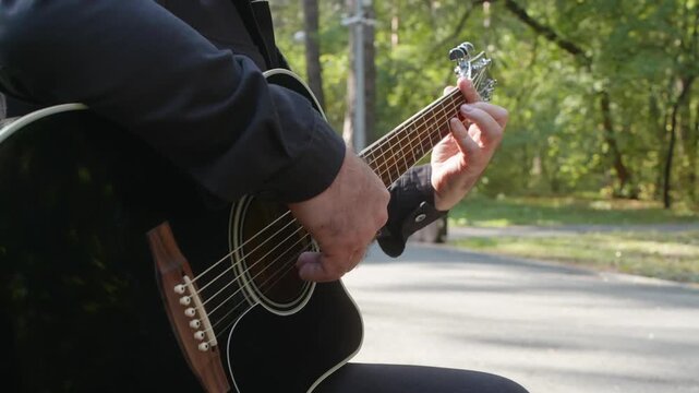 Skilled guitarist performing melodic acoustic tune amid verdant park landscape, capturing nuanced finger movements and natural surroundings with serene musical expression