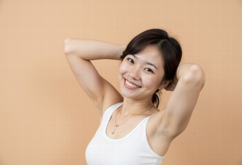 Fototapeta premium A happy young Asian woman with a radiant smile shows off her smooth, clean underarms, promoting body confidence, self-care, and effective hair removal beauty. 