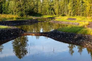 a quiet small town park featuring a reflective pond surrounded by greenery, Kempele Finland
