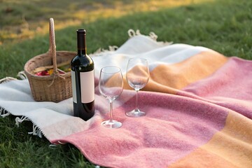 Romantic Picnic Setup with Wine Bottle and Glasses on Cozy Blanket in Outdoor Setting