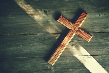 Wooden Cross on Rustic Wooden Surface with Sunlight and Shadows in Natural Setting