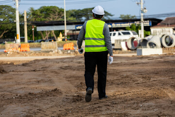 Fototapeta premium Civil engineer supervising the installation of concrete drainage pipes at a roadside construction site.
