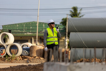 Civil engineer supervising the installation of concrete drainage pipes at a roadside construction site.