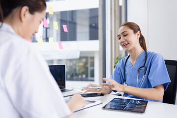 Obraz premium Female doctor and nurse working together with clipboard and laptop for in modern clinic.