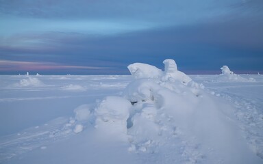 Obraz premium Snow covered landscape with rounded snowdrifts under twilight sky